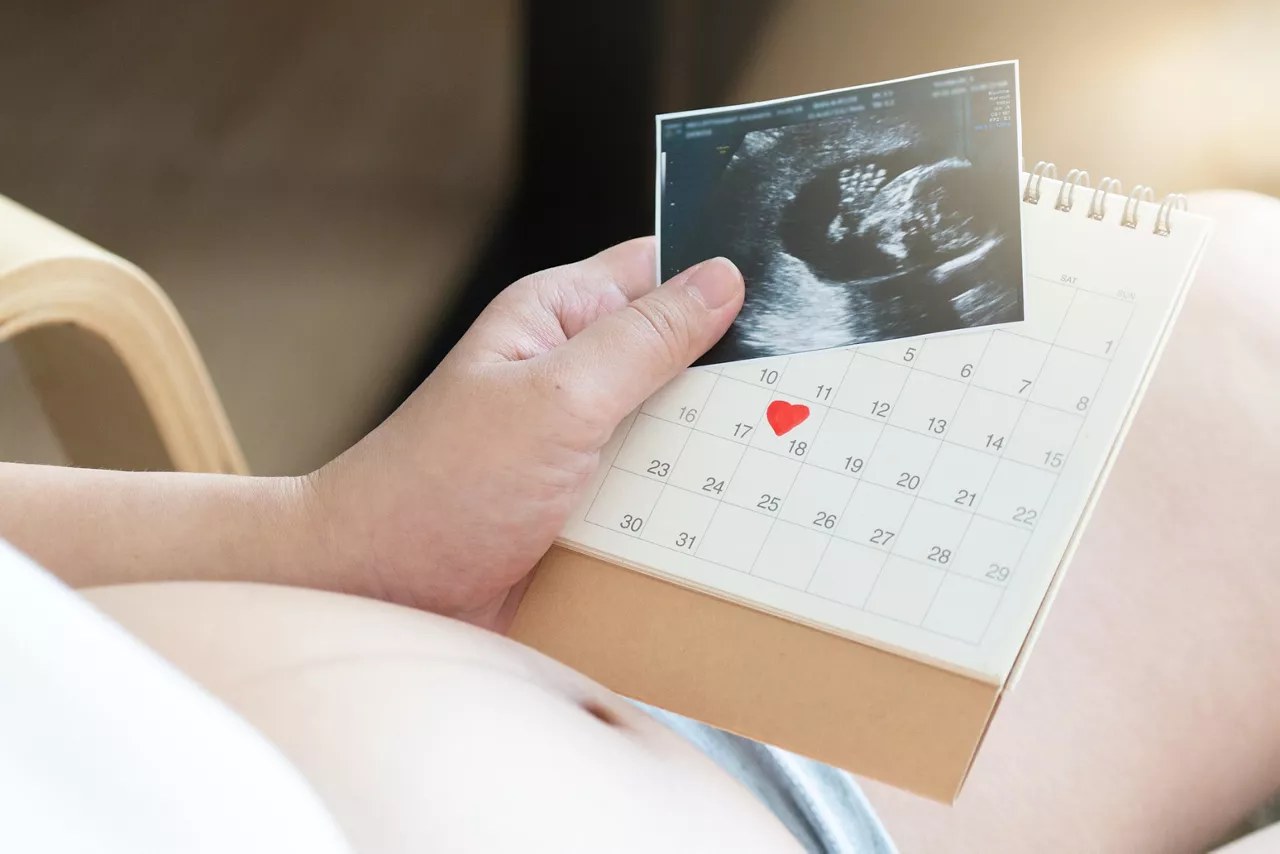 Femme enceinte consultant un calendrier pour calculer sa semaine de grossesse